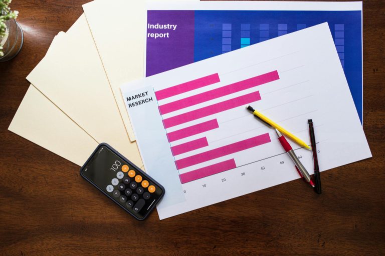 Top view of market research reports and calculator on a wooden desk, illustrating business analysis.